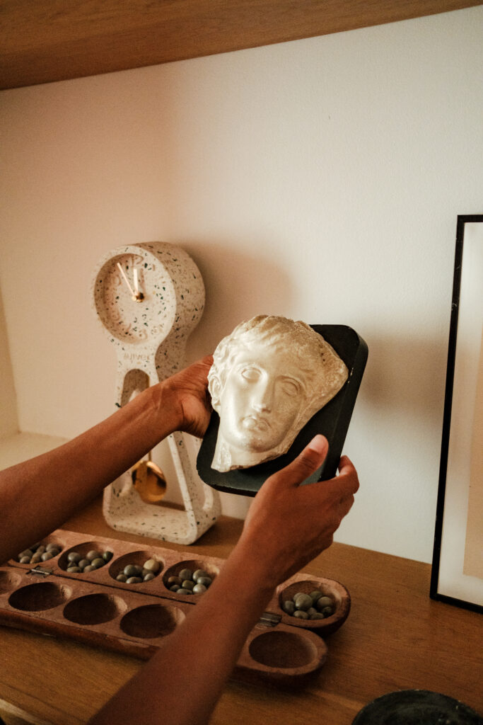 Mains de Estelle Louvouezo posant un accessoire de décoration sur une étagère